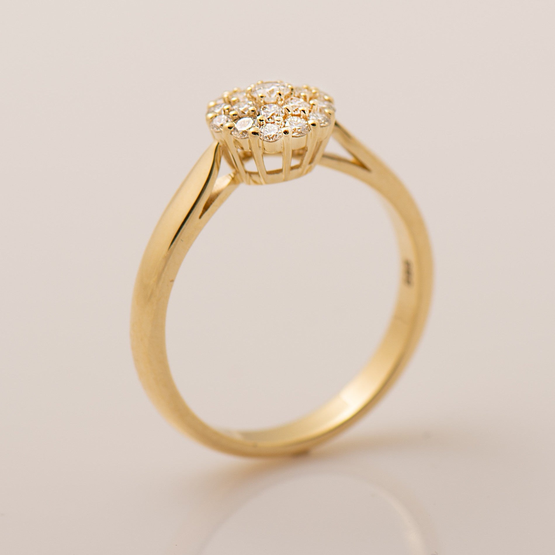 Gold ring with a diamond cluster on a light beige background